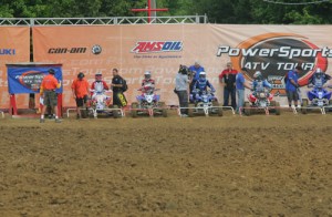Well prepared racers, TV cameras, refs, officials and a giant Powersport ATV Tour backdrop complete the scene at the starting gate. 